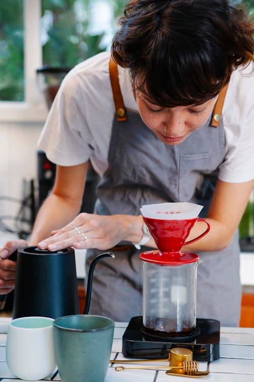 Free Pensive barista preparing pour over coffee in cafe in daytime Stock Photo