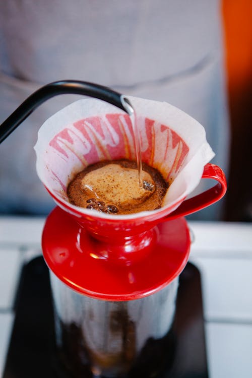 Hot coffee preparing in bright red cup with special equipment