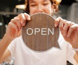Happy woman showing wooden signboard saying open