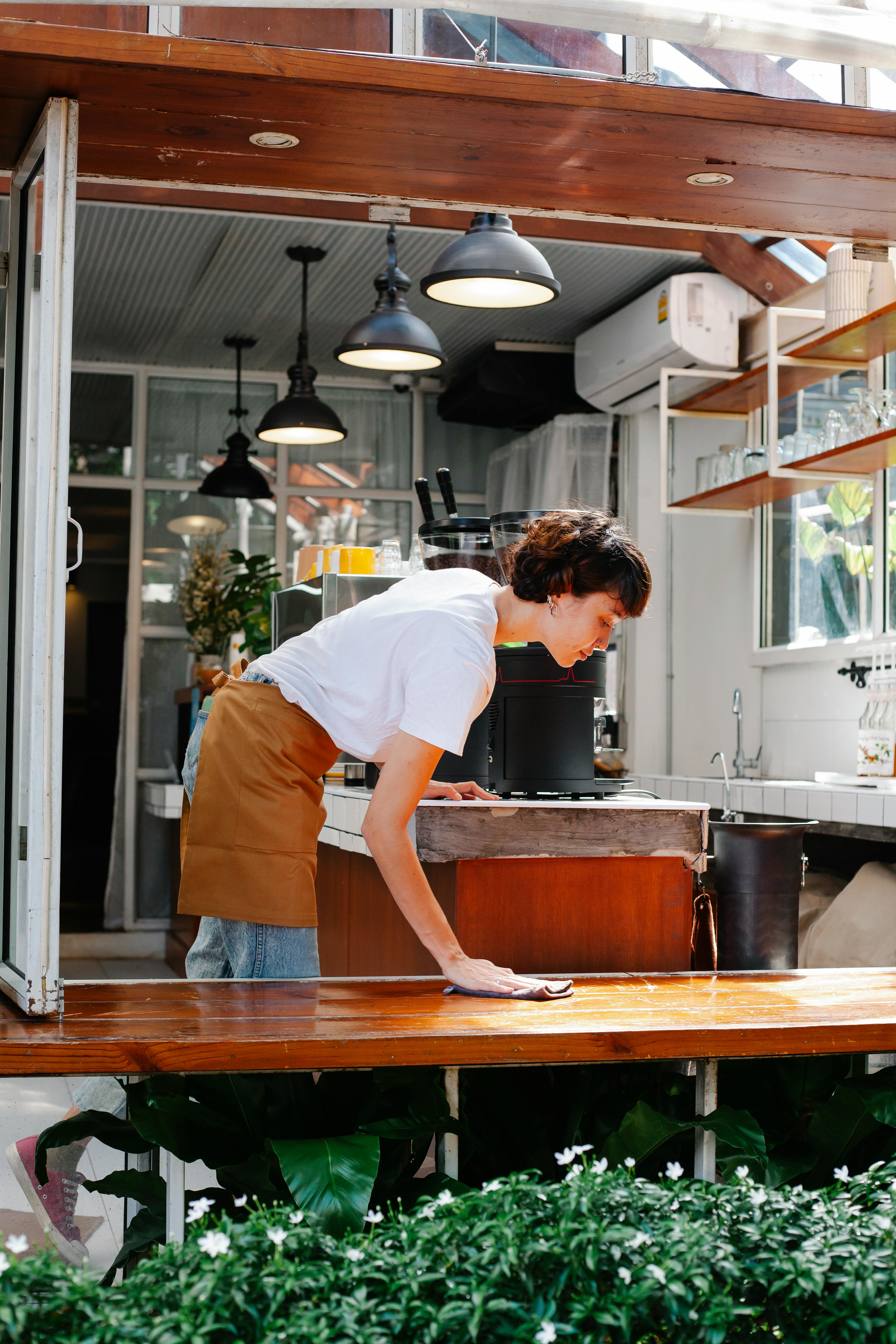 busy woman cleaning wooden counter in cafe