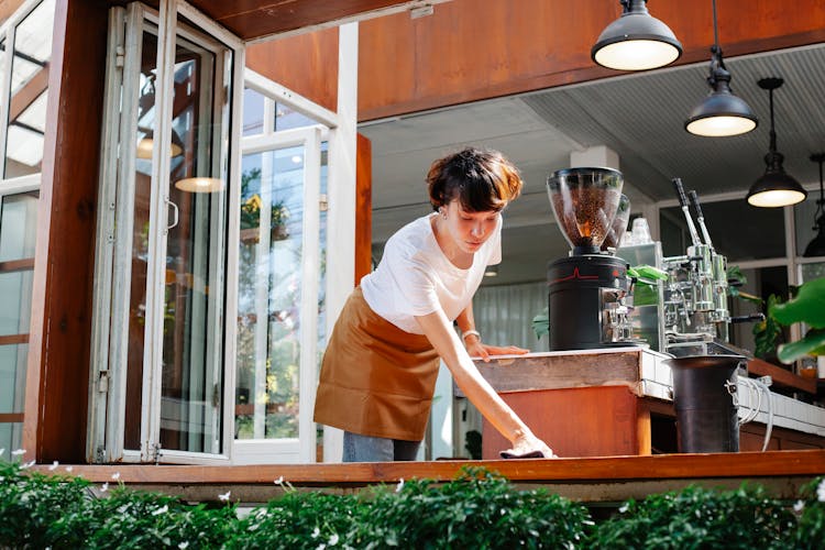 Woman Wiping Wooden Board Of Cafe