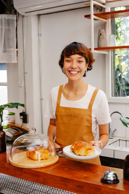 Free Cheerful woman serving croissants in cafe Stock Photo