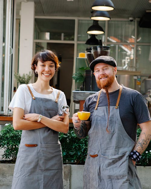 Positive coworkers in aprons on terrace of cafe