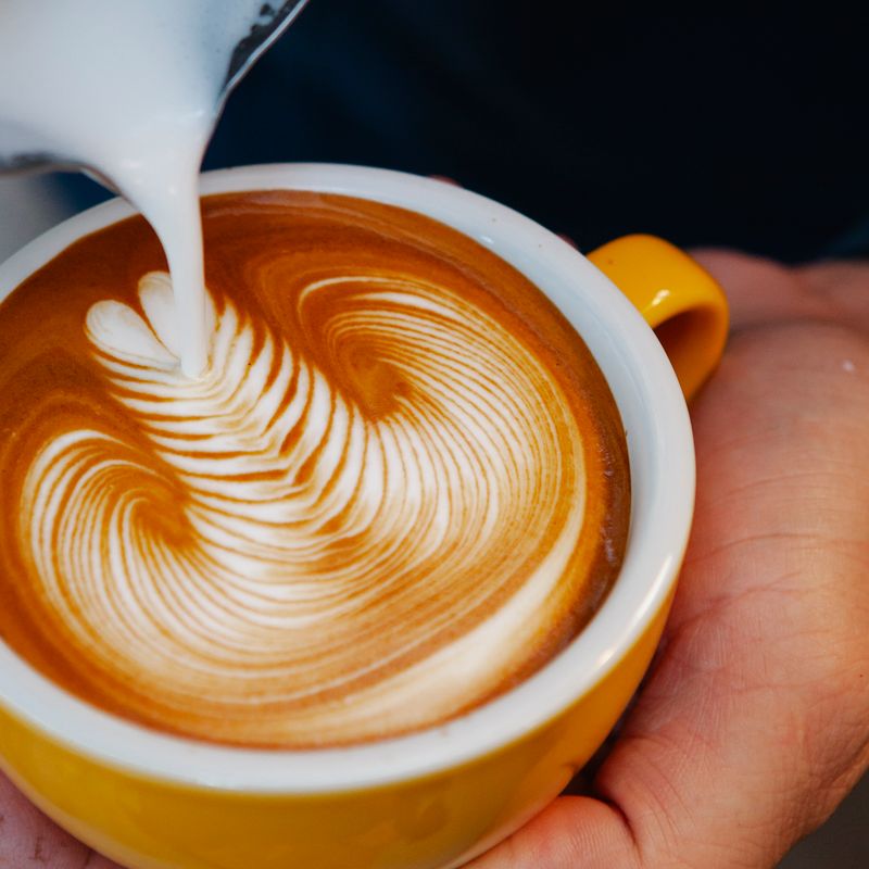 Barista pouring latte art into a mug