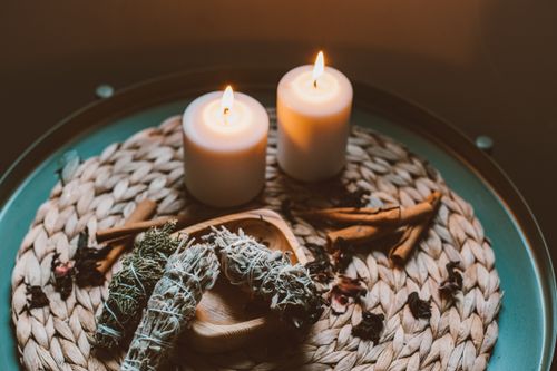Free Warm and cozy candlelit setup featuring incense and herbs on a woven plate. Stock Photo