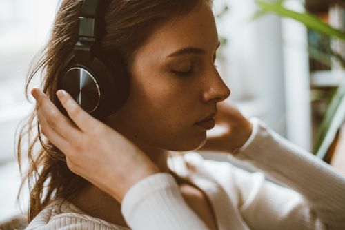Free Side profile of a woman with headphones relaxing in a calm indoor setting. Stock Photo