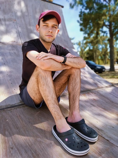 Free A Man in Black Shirt Sitting on a Wooden Surface Stock Photo