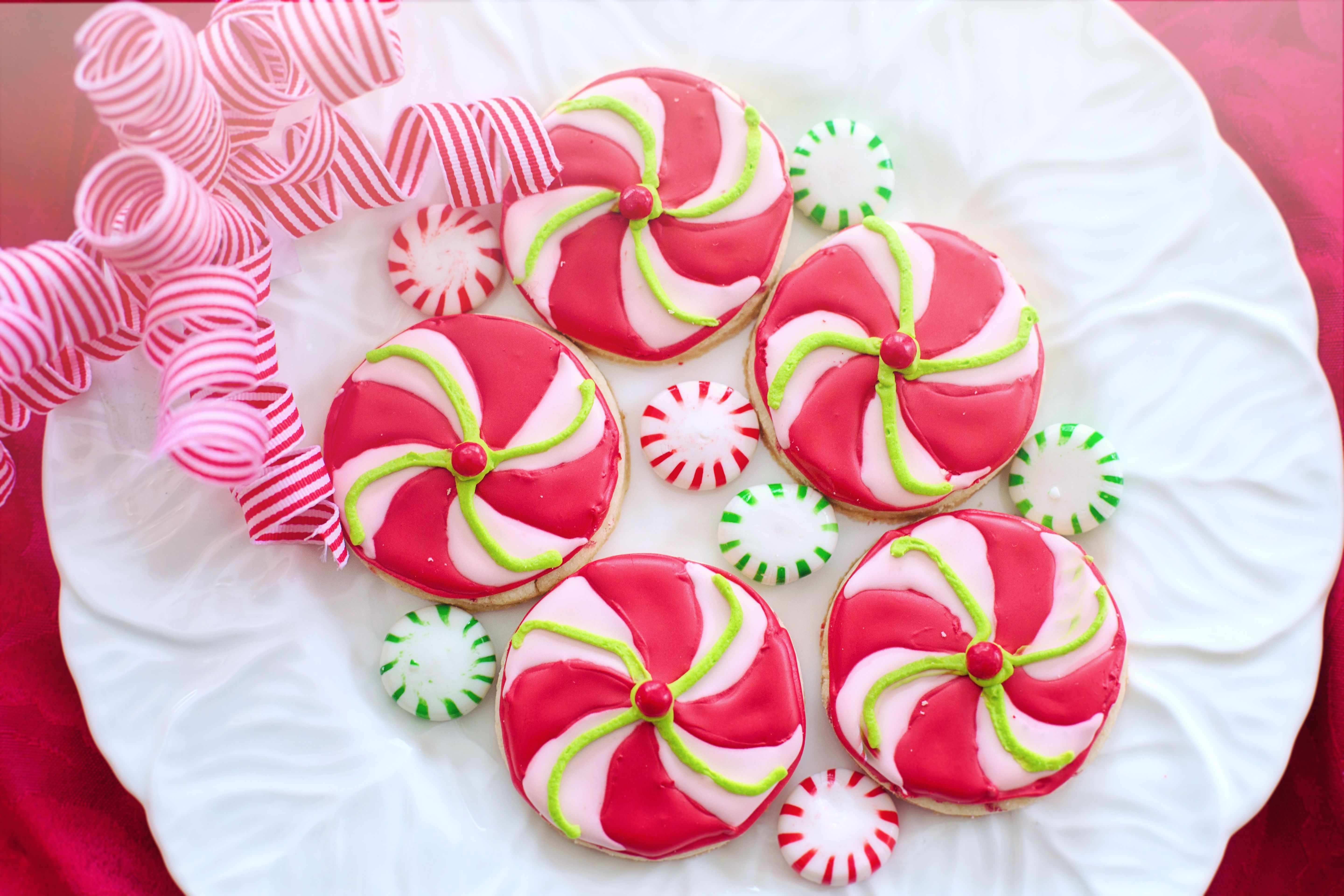 Colorful peppermint swirl cookies on a white plate, perfect for holiday celebrations.