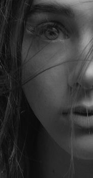 Close-up black and white portrait highlighting a woman's expressive eye and delicate features.