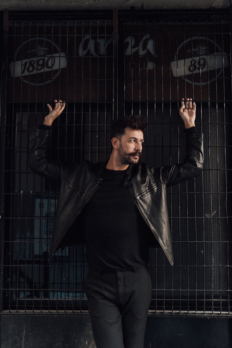 Trendy Man Standing With Arms Raised Against Grid Wall