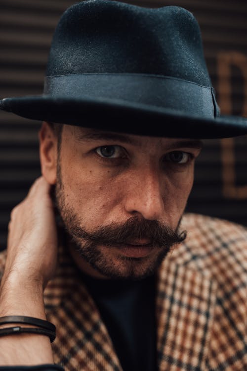 Confident well dressed man in hat touching neck