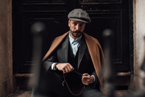 Serious elegant man in formal suit sitting on doorway