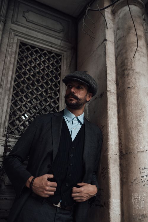 Free Pondering bearded classy man in posh suit coat and hat standing outside stone building door and looking away in deep thoughts Stock Photo