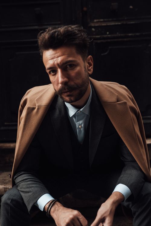 Free Pensive man with beard and mustache in stylish classy clothes sitting on stairs of building in city and looking at camera in daylight Stock Photo
