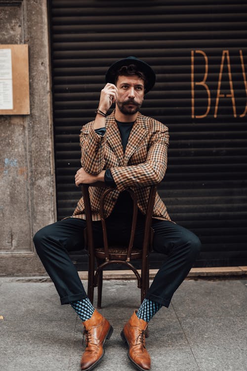 Stylish man sitting on chair near building