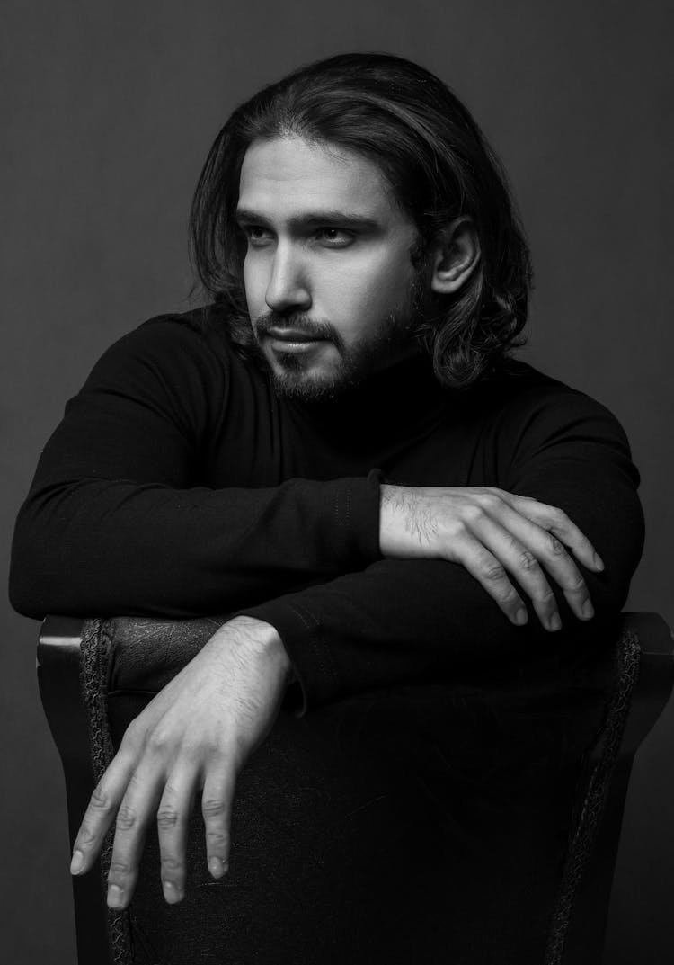 Confident Adult Bearded Man Sitting On Chair And Looking Away