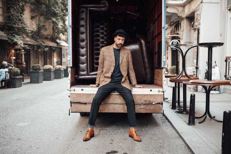 Fashionable Man Sitting On Trunk Of Truck