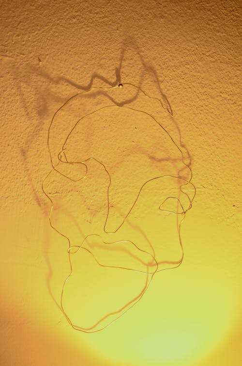Minimalist abstract artwork made of wire lightening by shiny lamp on white wall