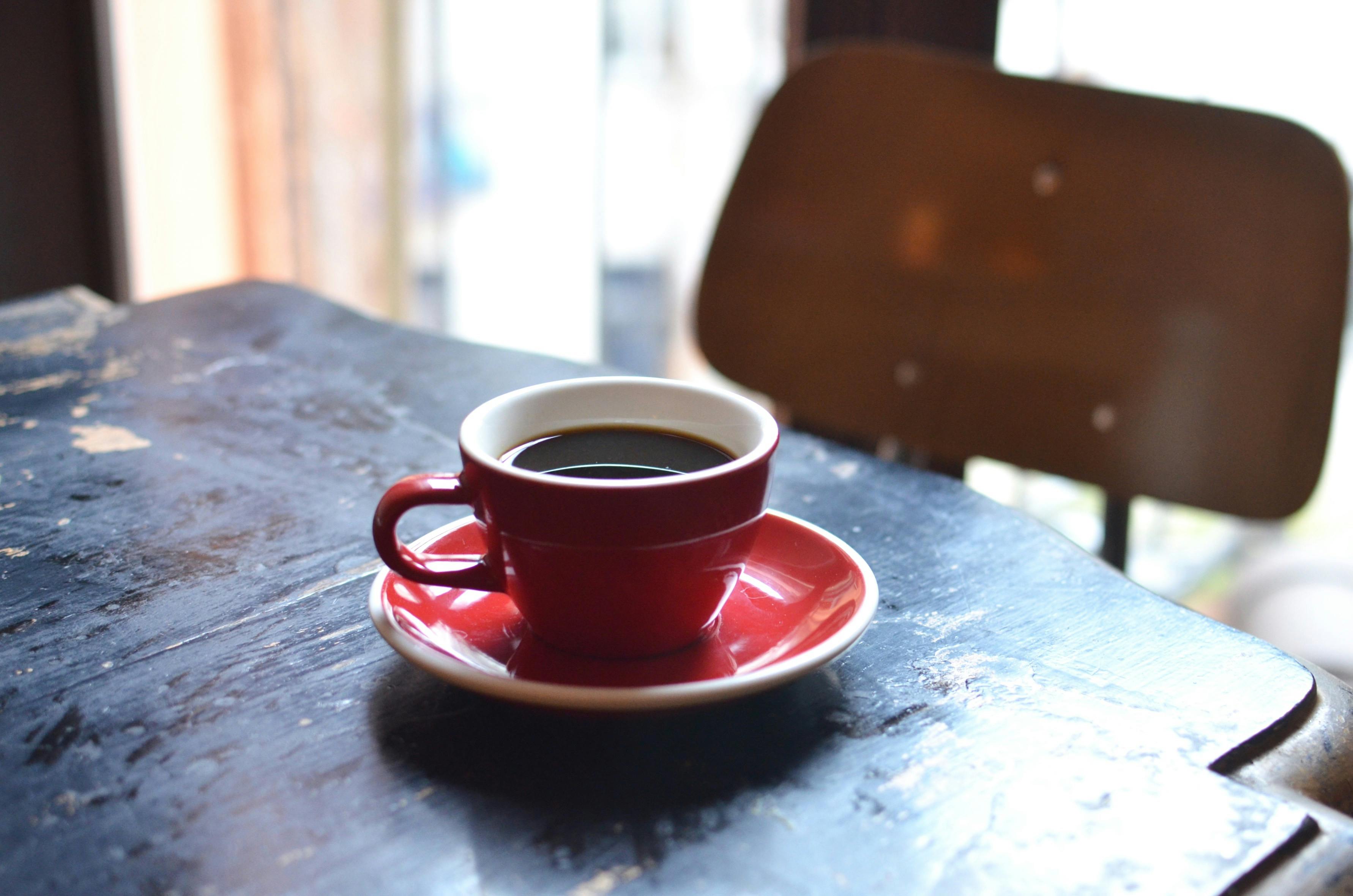 coffee in ceramic cup with saucer on table near chair