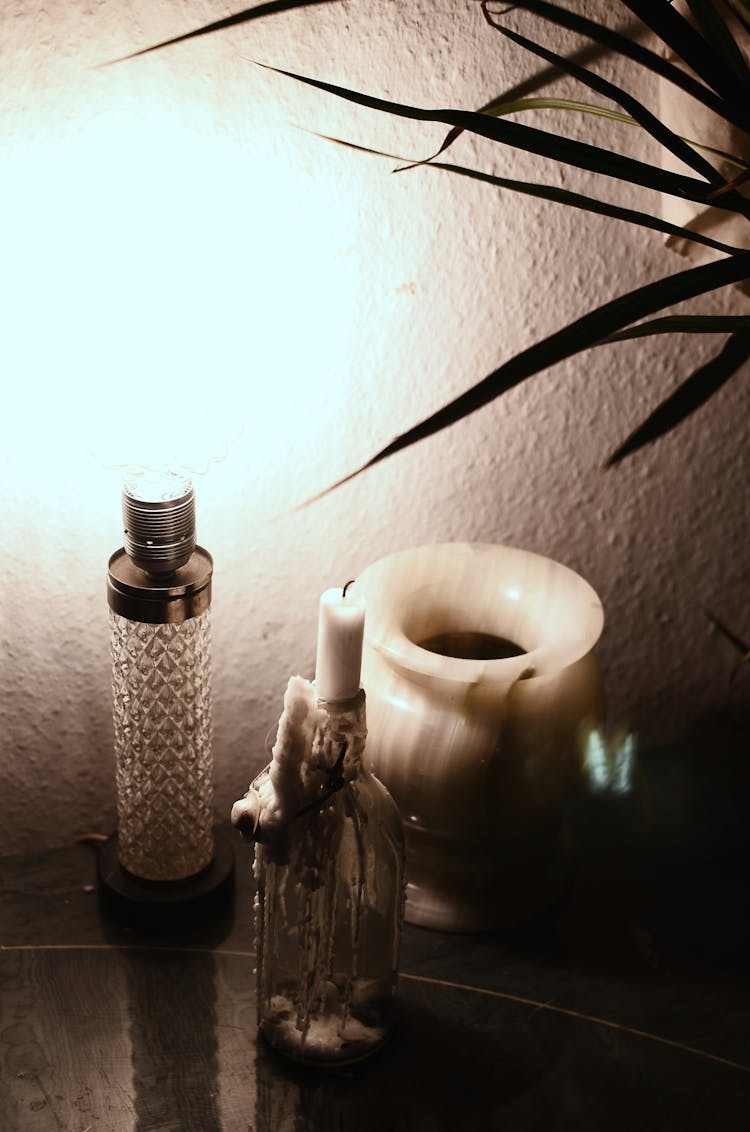 Glowing Lamp And Candle On Table In Dark Room