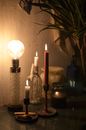 Vintage glowing lamp placed on table near burning candles in candlesticks in dark room