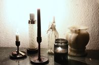 Glowing lamp illuminating dark room placed on table near burning candles on candlesticks and empty ceramic vase