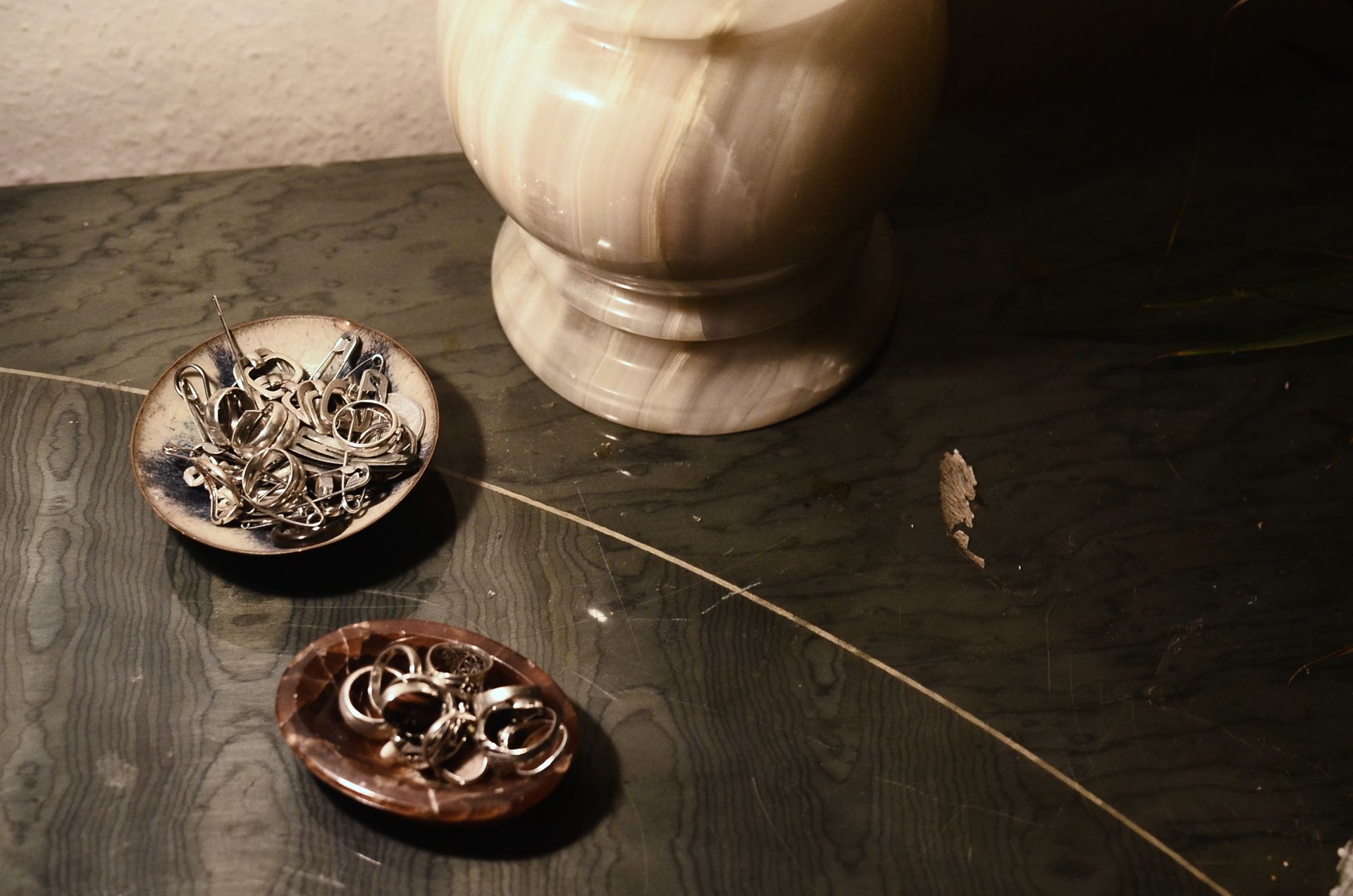 A stylish onyx lamp with jewelry in decorative bowls on a luxurious surface.