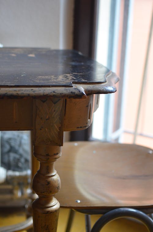 Living room interior with aged wooden table with rounded edges and chair at home in daylight