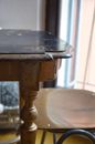 Living room interior with aged wooden table with rounded edges and chair at home in daylight