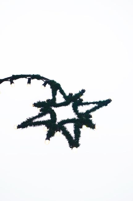 Fotomural Imagen minimalista de una decoración navideña en forma de estrella con luces sobre un fondo blanco.