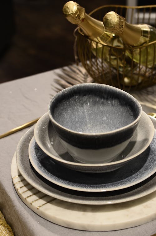 Served table with ceramic bowls and plates near metal basket with bottles of alcoholic drinks