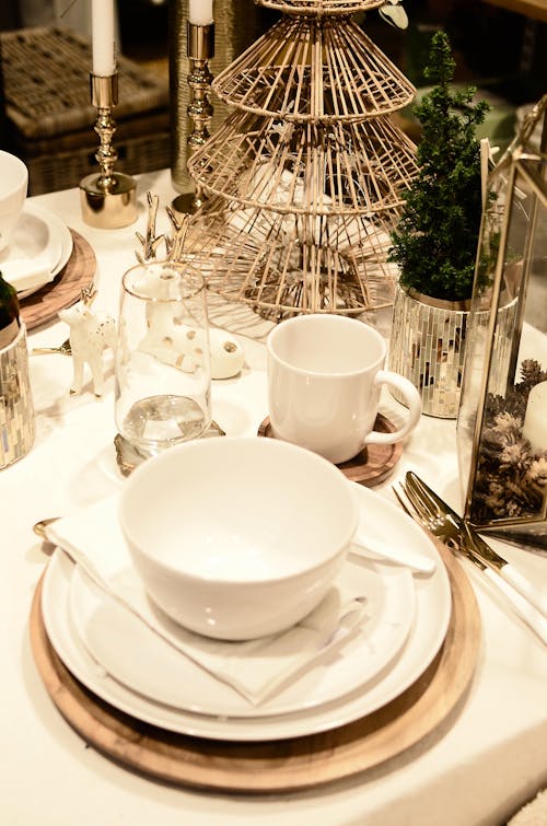 From above of served table with set of dishware near decorative deer statuettes and small Christmas tree during festive event in restaurant