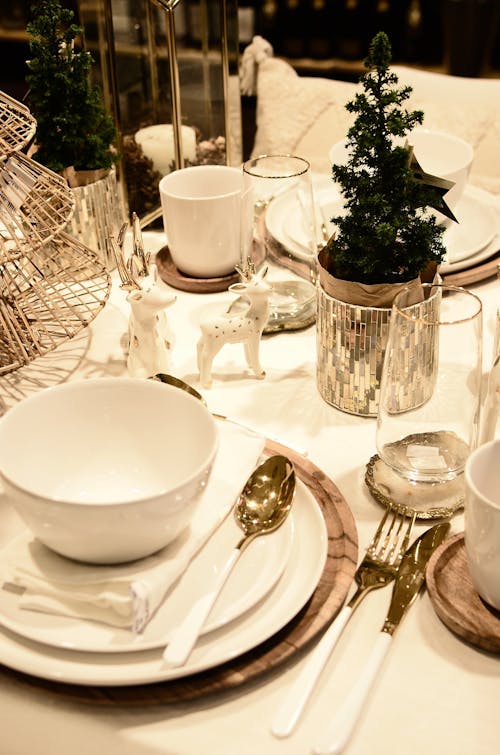 From above of served table with small Christmas tree and decorative deer statuettes during festive event in restaurant