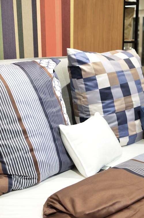 Creative design of assorted cushions with ornament on soft bed against color palette in bedding shop