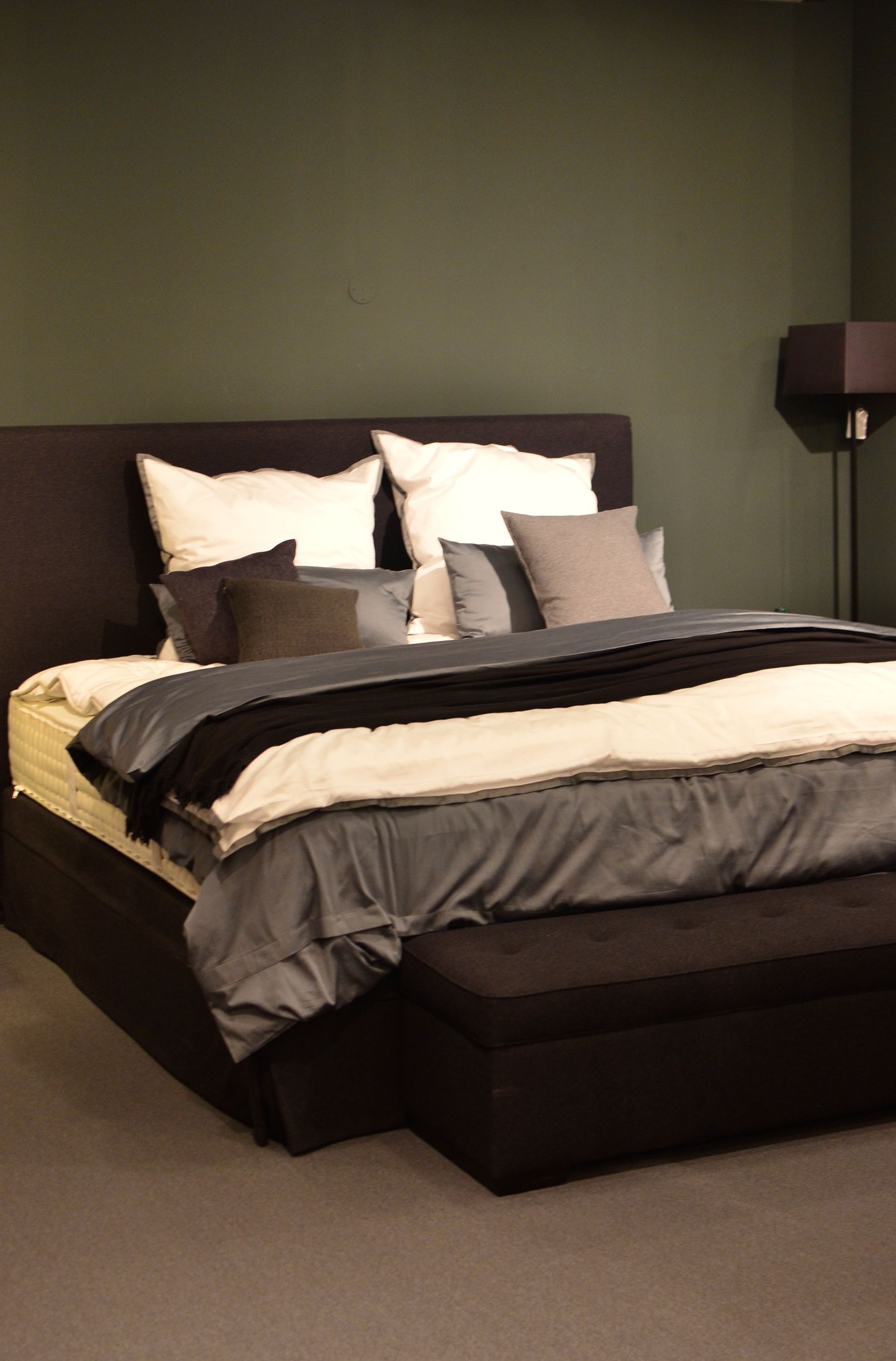 Bedroom with a deep teal wall, pale bedding and warm timber furniture