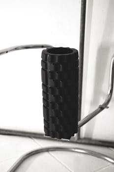 Close-up of a black textured foam roller on a metallic gym stand, emphasizing fitness equipment.