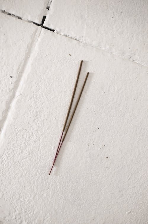 Thin incense sticks on white tiled floor