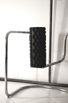 Black textured foam roller on a sleek metal stand, ideal for fitness and massage therapy.