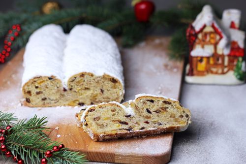 Free Traditional Christmas Stollen with powdered sugar and fruits on a wooden cutting board. Stock Photo