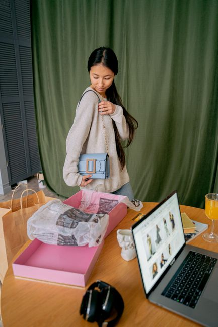 A young woman delights in unboxing her new handbag while shopping online at home. - Understanding Common Scams in Online Handbag Shopping
