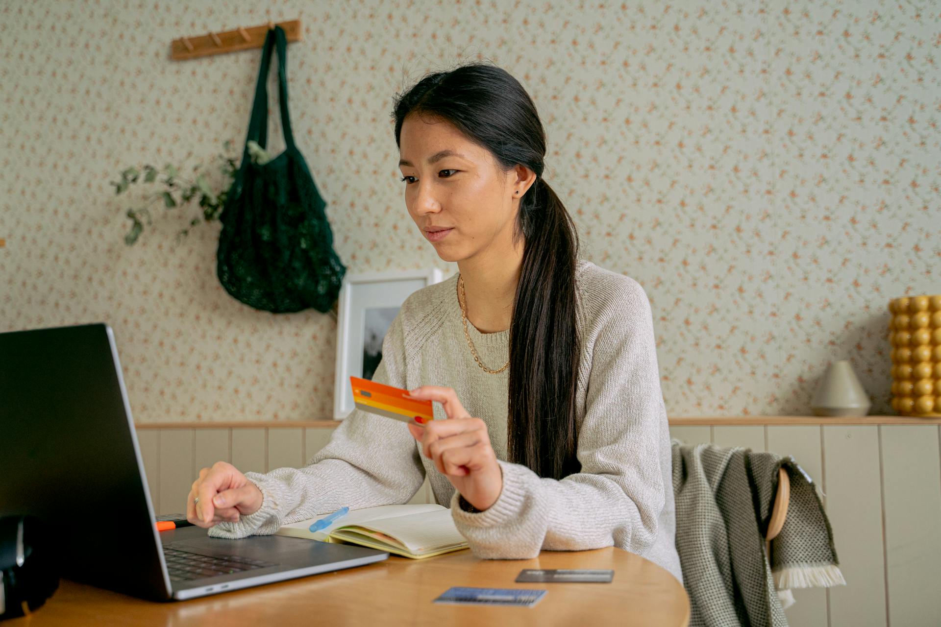 Young Asian woman using a laptop and credit card for online shopping at home.