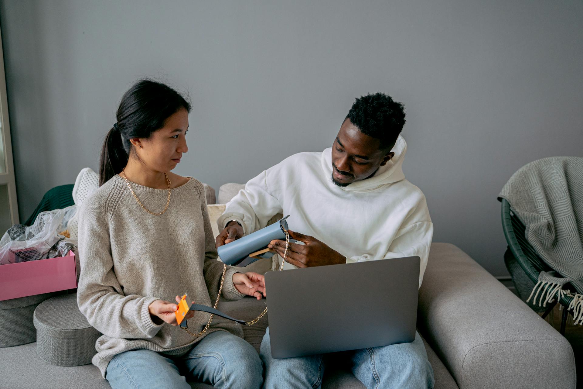 Diverse couple making an online purchase using a laptop and credit card in cozy setting.