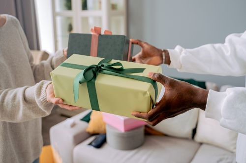 Free Two people exchanging wrapped gifts indoors, highlighting a shared moment of giving. Stock Photo