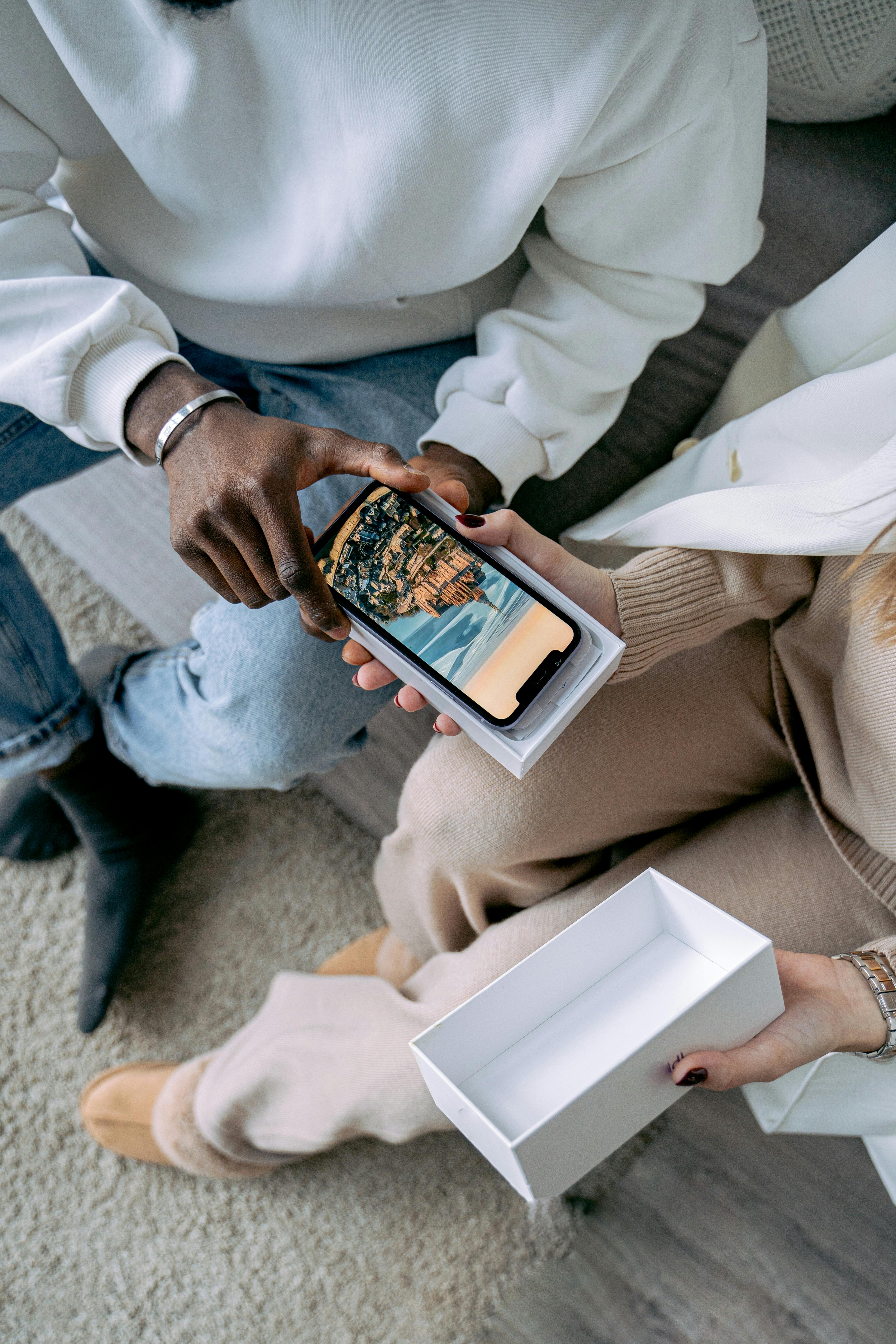 High angle view of a couple unpacking a new smartphone on a sofa.