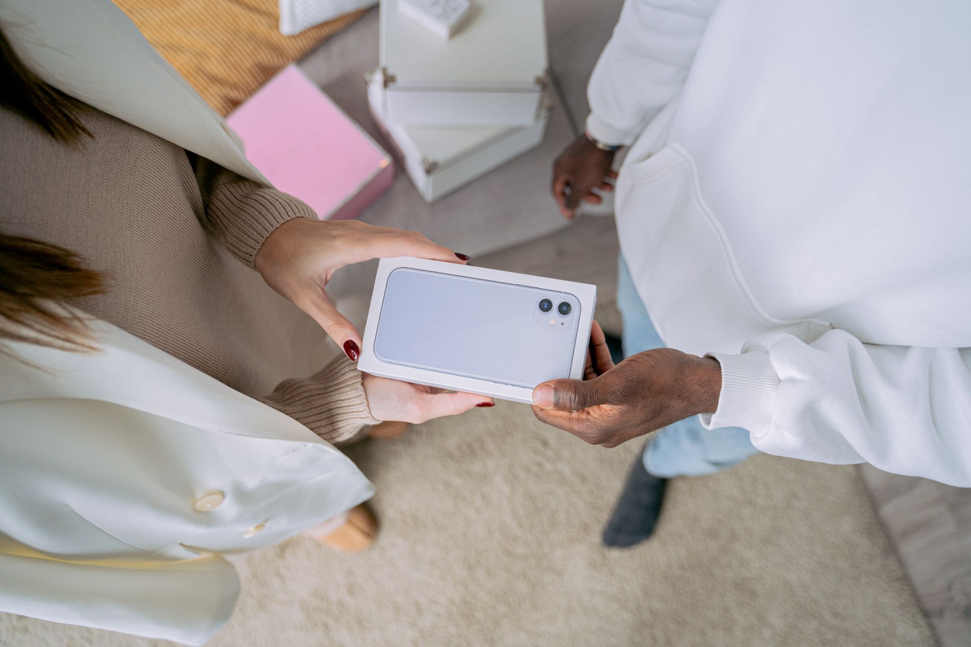Adults exchanging a smartphone gift indoors, highlighting modern technology and joyful sharing.