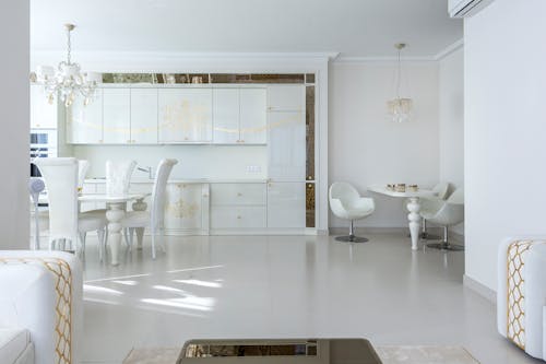 Interior of contemporary apartment with light dining zone and white furniture in kitchen