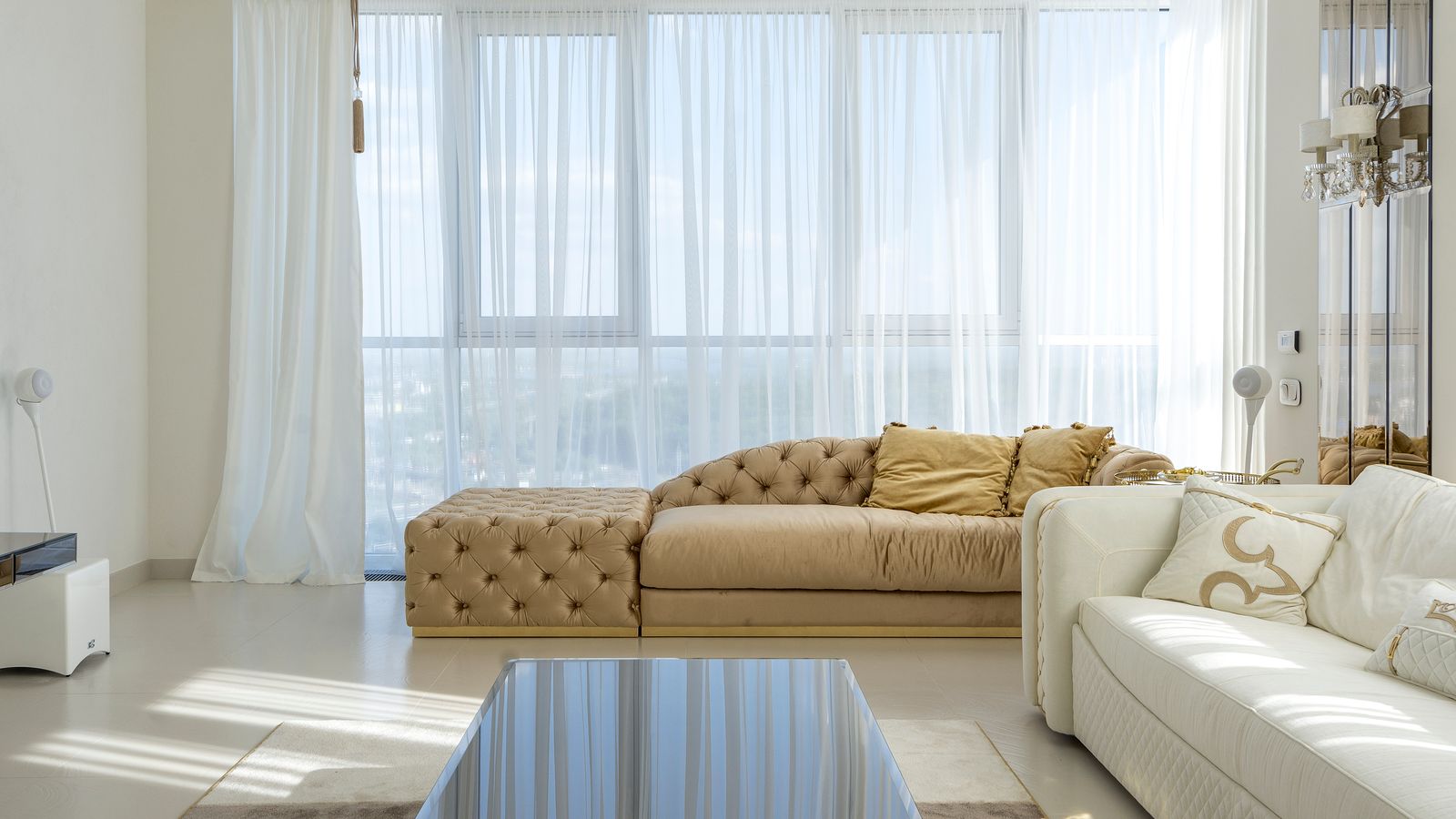 Bright living room with beige and white sofas and a glass coffee table