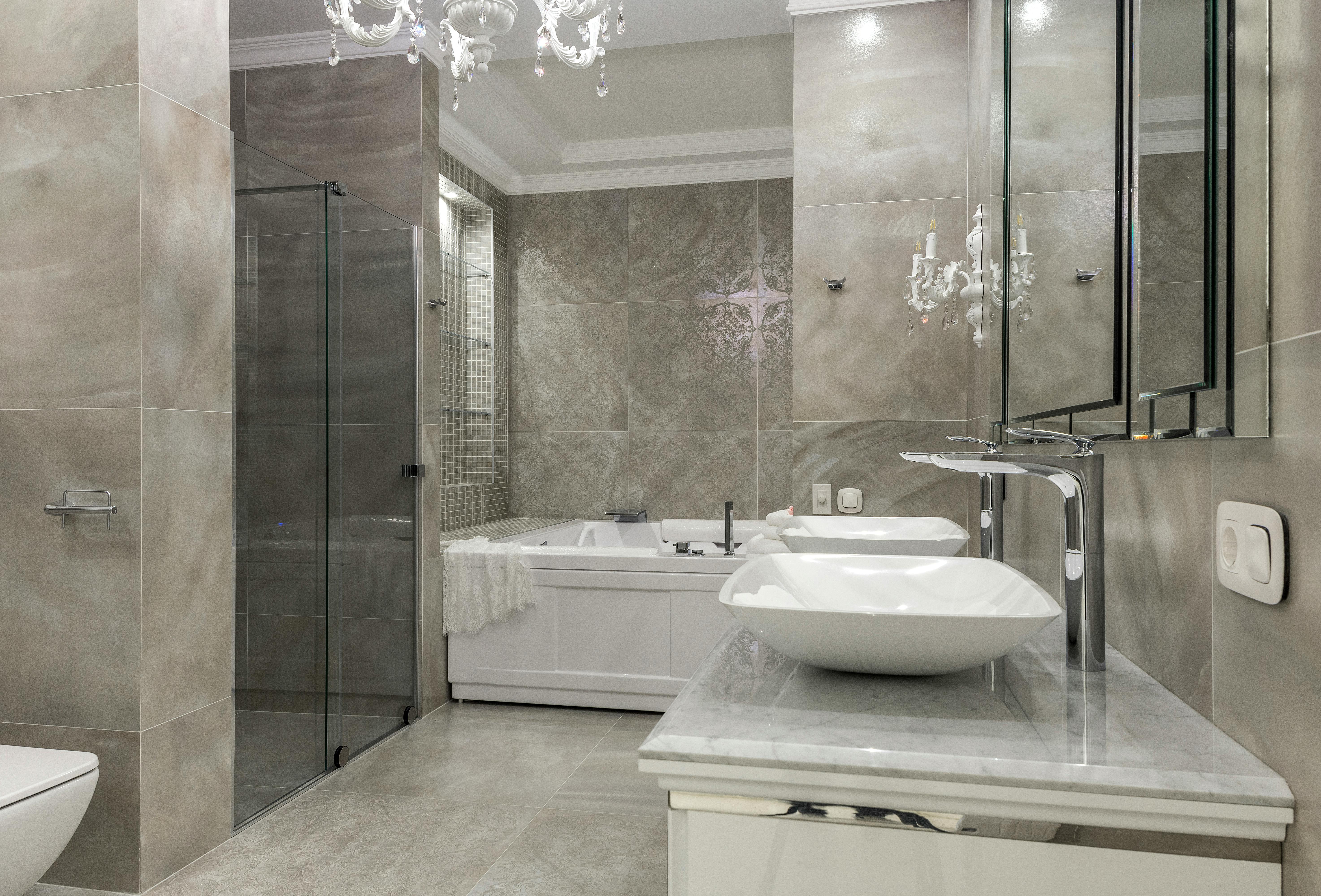 Luxury interior of spacious bathroom with tiled walls and floor double vessel sink vanity and chandelier