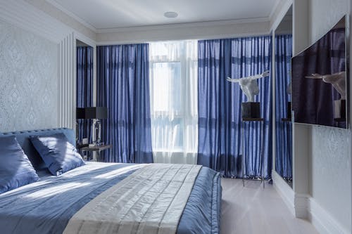 Pearl and blue interior of modern bedroom with comfortable bed and elegant decorations