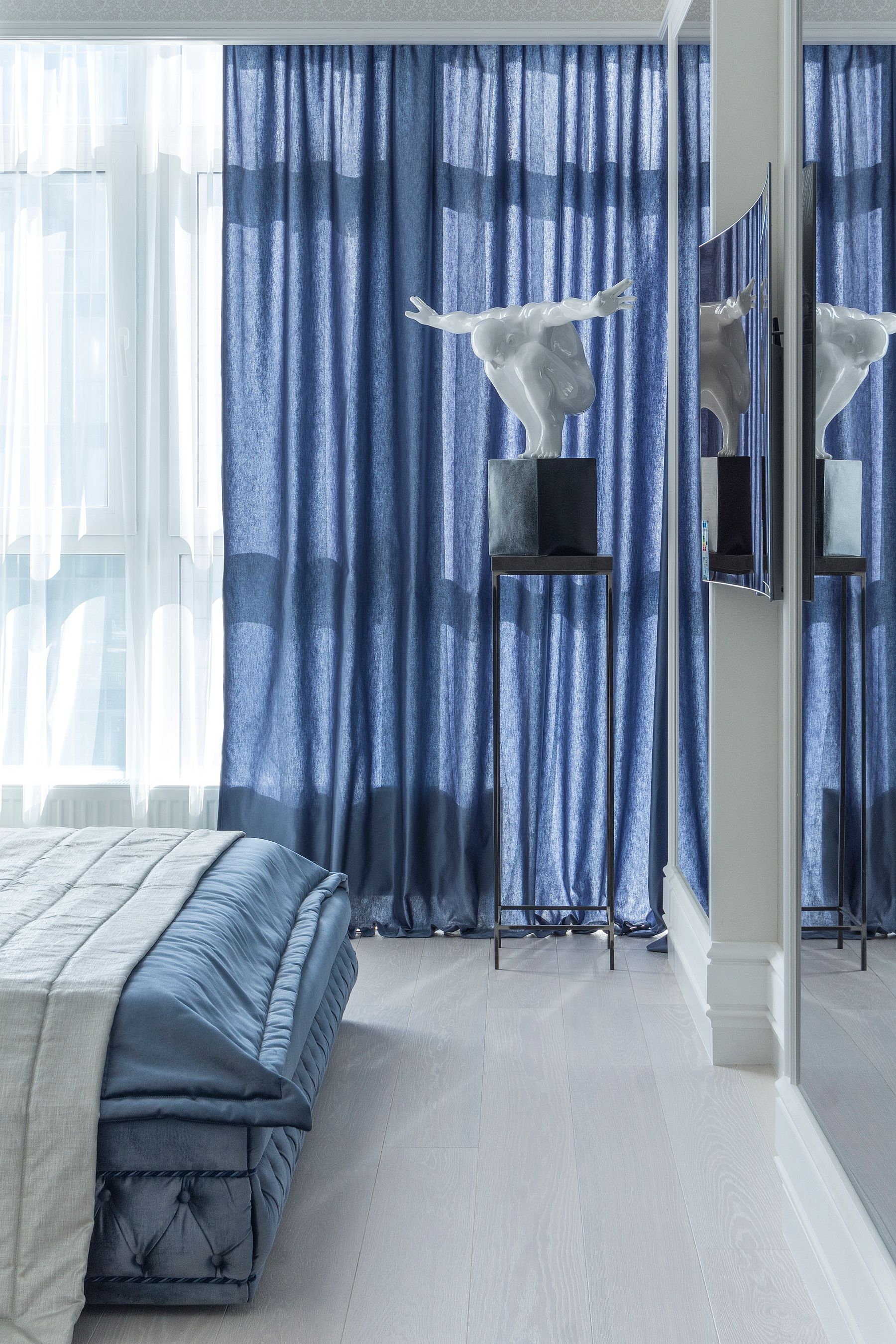 Pearl-toned bedroom with a pale upholstered bed, blue pillows and coordinated blue accents